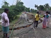 People stand near the erosion caused by the Kopilli River on a section of the PWD road near Bagalajan, which connects Raha to Kampur, in Nag...