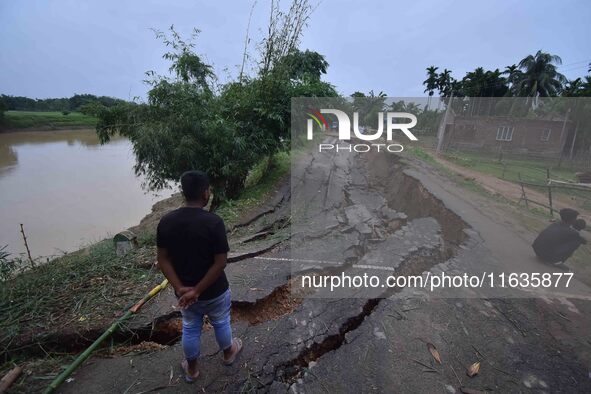 People stand near the erosion caused by the Kopilli River on a section of the PWD road near Bagalajan, which connects Raha to Kampur, in Nag...