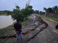 People stand near the erosion caused by the Kopilli River on a section of the PWD road near Bagalajan, which connects Raha to Kampur, in Nag...