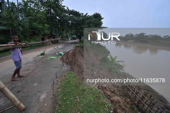 People stand near the erosion caused by the Kopilli River on a section of the PWD road near Bagalajan, which connects Raha to Kampur, in Nag...