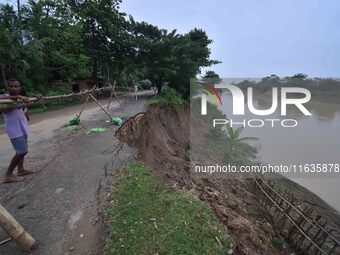 People stand near the erosion caused by the Kopilli River on a section of the PWD road near Bagalajan, which connects Raha to Kampur, in Nag...