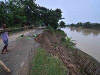 People stand near the erosion caused by the Kopilli River on a section of the PWD road near Bagalajan, which connects Raha to Kampur, in Nag...