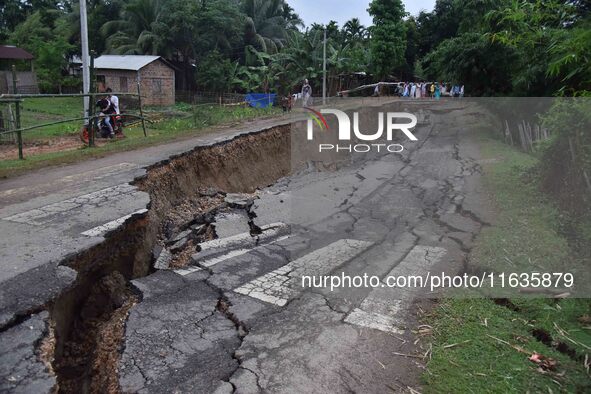 People stand near the erosion caused by the Kopilli River on a section of the PWD road near Bagalajan, which connects Raha to Kampur, in Nag...