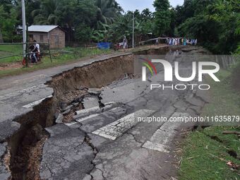 People stand near the erosion caused by the Kopilli River on a section of the PWD road near Bagalajan, which connects Raha to Kampur, in Nag...