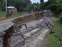 People stand near the erosion caused by the Kopilli River on a section of the PWD road near Bagalajan, which connects Raha to Kampur, in Nag...