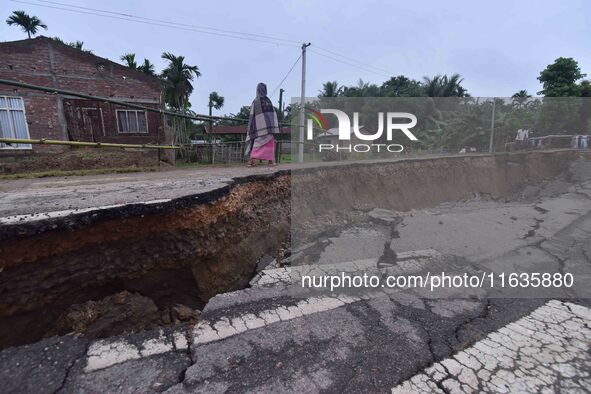 People stand near the erosion caused by the Kopilli River on a section of the PWD road near Bagalajan, which connects Raha to Kampur, in Nag...