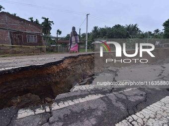 People stand near the erosion caused by the Kopilli River on a section of the PWD road near Bagalajan, which connects Raha to Kampur, in Nag...