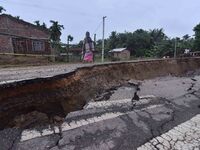 People stand near the erosion caused by the Kopilli River on a section of the PWD road near Bagalajan, which connects Raha to Kampur, in Nag...