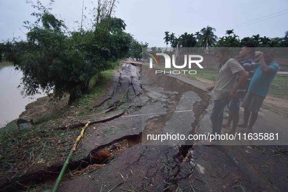 People stand near the erosion caused by the Kopilli River on a section of the PWD road near Bagalajan, which connects Raha to Kampur, in Nag...