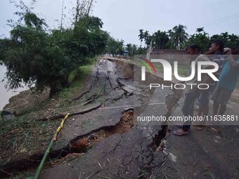 People stand near the erosion caused by the Kopilli River on a section of the PWD road near Bagalajan, which connects Raha to Kampur, in Nag...