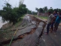 People stand near the erosion caused by the Kopilli River on a section of the PWD road near Bagalajan, which connects Raha to Kampur, in Nag...