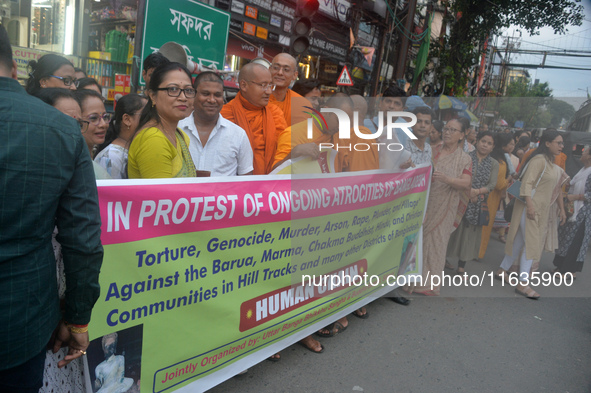 Members of the Buddhist community hold a banner as they participate in a silent protest and human chain against the ongoing violence and atr...