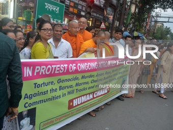 Members of the Buddhist community hold a banner as they participate in a silent protest and human chain against the ongoing violence and atr...