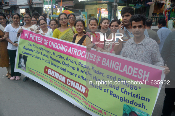 Members of the Buddhist community hold a banner as they participate in a silent protest and human chain against the ongoing violence and atr...