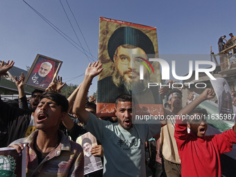 Shiite Muslims carry pictures of Hezbollah leader Hassan Nasrallah as they shout anti-Israel slogans during a demonstration to show their an...