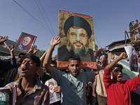 Shiite Muslims carry pictures of Hezbollah leader Hassan Nasrallah as they shout anti-Israel slogans during a demonstration to show their an...