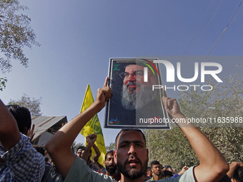 A Shiite Muslim carries a picture of Hezbollah leader Hassan Nasrallah during a demonstration to show his anger towards the killing of a lea...