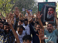 Shiite Muslims carry pictures of Hezbollah leader Hassan Nasrallah as they shout anti-Israel slogans during a demonstration to show their an...