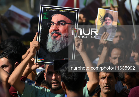 Shiite Muslims carry pictures of Hezbollah leader Hassan Nasrallah as they shout anti-Israel slogans during a demonstration to show their an...