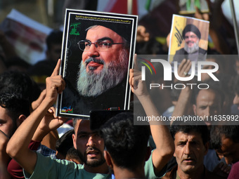 Shiite Muslims carry pictures of Hezbollah leader Hassan Nasrallah as they shout anti-Israel slogans during a demonstration to show their an...