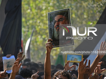 A Shiite Muslim carries a picture of Hezbollah leader Hassan Nasrallah during a demonstration to show his anger towards the killing of a lea...