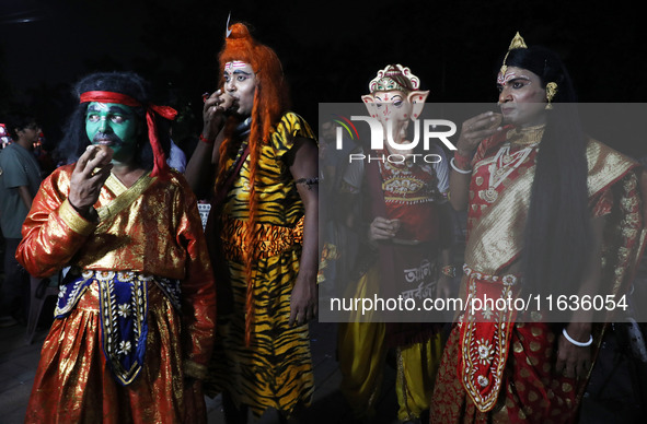 Performers dress as Hindu gods, and a performer dressed as goddess Durga drinks tea at a tea stall in Kolkata, India, on October 4, 2024. Th...