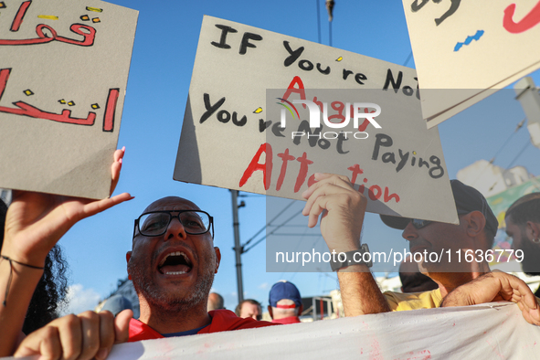 A man shouts slogans against President Kais Saied as he raises a placard that reads, ''If you are not angry, you are not paying attention,''...