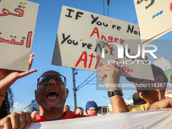 A man shouts slogans against President Kais Saied as he raises a placard that reads, ''If you are not angry, you are not paying attention,''...