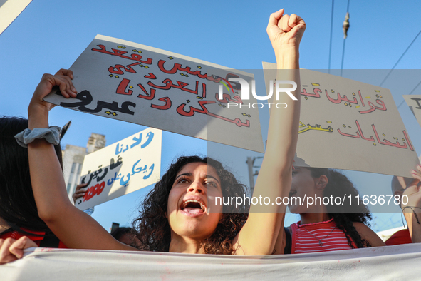 A young woman shouts slogans against President Kais Saied as she raises a placard that reads in Arabic, ''five years in power and nothing do...