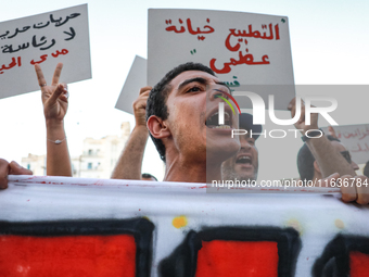 A young man shouts slogans against President Kais Saied, while others raise placards during a demonstration organized by the Tunisian Networ...