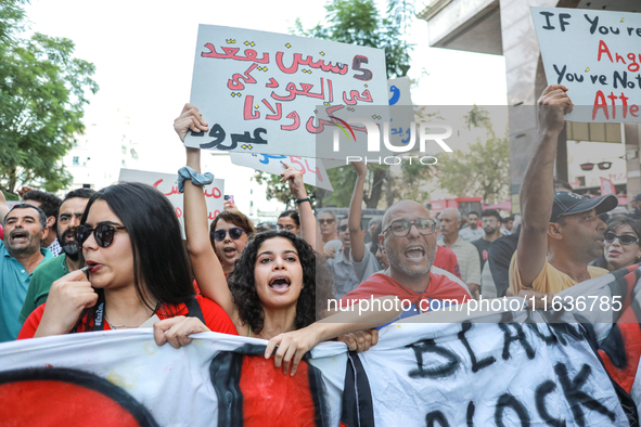 A young woman shouts slogans against President Kais Saied as she raises a placard that reads in Arabic, ''five years in power and nothing do...