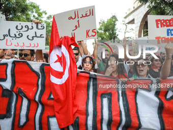 Demonstrators shout slogans against President Kais Saied as they raise placards and the national flag of Tunisia during a demonstration orga...