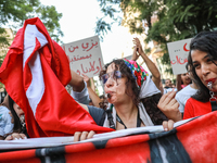 A young woman blows a whistle as she holds the national flag of Tunisia during a demonstration organized by the Tunisian Network for Rights...