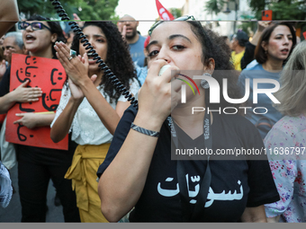 A young woman wears a T-shirt that reads ''Feminists'' in Arabic and shouts slogans against President Kais Saied on a megaphone during a dem...