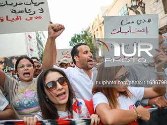 A woman (L) raises a placard that reads in Arabic, ''freedom, freedom, no presidency for lifetime,'' as others raise fists while shouting sl...