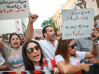 A woman (L) raises a placard that reads in Arabic, ''freedom, freedom, no presidency for lifetime,'' as others raise fists while shouting sl...