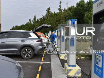 Electric vehicles charge at an electric vehicle charging station on a street in Fuyang, China, on October 5, 2024. (