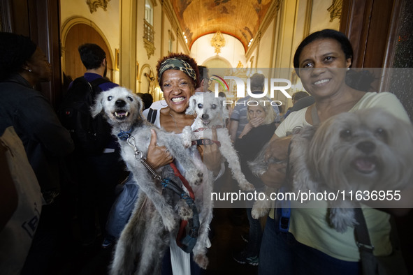 Devotees raise their pets to receive holy water blessings during a mass to bless pets and animals as part of 'World Animal Day' at Iglesia d...