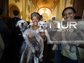 Devotees raise their pets to receive holy water blessings during a mass to bless pets and animals as part of 'World Animal Day' at Iglesia d...