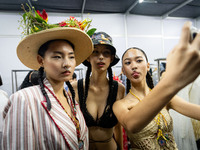 Models wear creations by ISSUE and get ready backstage before walking on the runway during Day 3 of Bangkok International Fashion Week at Si...