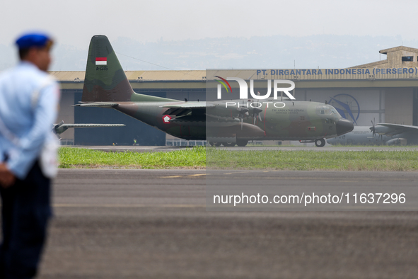 A soldier watches a plane land during the TNI Transport Aircraft Static Show event to commemorate the 79th Anniversary of the TNI at Husein...