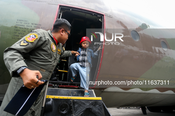 A soldier helps visitors get off a parked aircraft during the TNI Transport Aircraft Static Show event to commemorate the 79th Anniversary o...