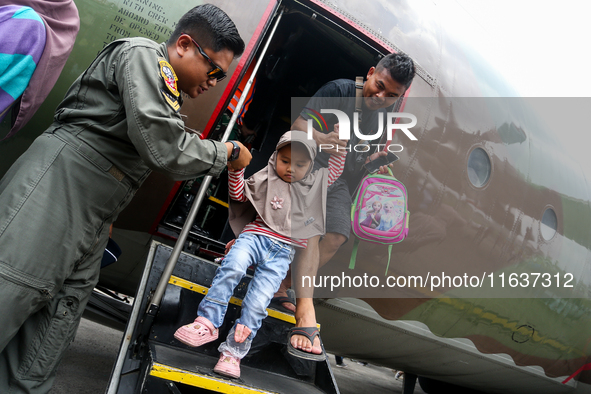 A soldier helps visitors get off a parked aircraft during the TNI Transport Aircraft Static Show event to commemorate the 79th Anniversary o...