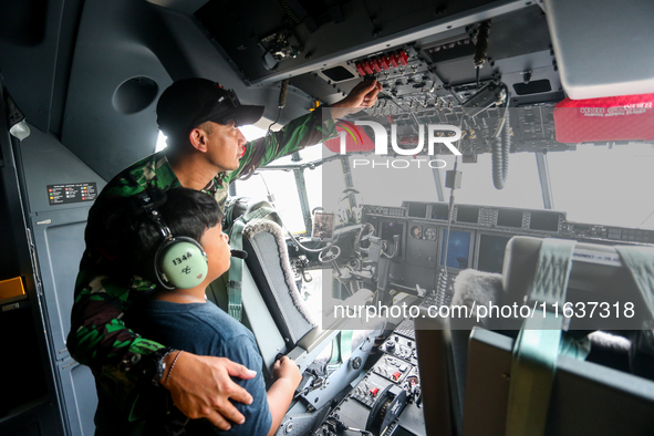 A soldier educates a child about the features inside a parked aircraft during the TNI Transport Aircraft Static Show event to commemorate th...