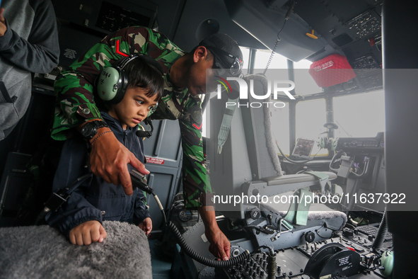 A soldier educates a child about the features inside a parked aircraft during the TNI Transport Aircraft Static Show event to commemorate th...