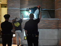 New York City Police Department crime scene investigators swab for evidence outside the One Carnegie Hill luxury rental apartment complex lo...