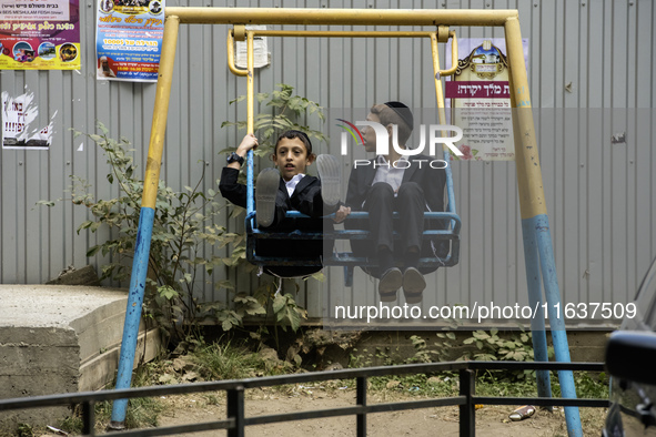 Children who are Ultra-Orthodox Jewish pilgrims swing on a swing on a street near the tomb of Rabbi Nachman while celebrating Rosh Hashanah,...