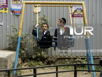 Children who are Ultra-Orthodox Jewish pilgrims swing on a swing on a street near the tomb of Rabbi Nachman while celebrating Rosh Hashanah,...