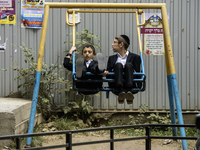 Children who are Ultra-Orthodox Jewish pilgrims swing on a swing on a street near the tomb of Rabbi Nachman while celebrating Rosh Hashanah,...