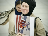 A woman folds a placard with Israeli and American flags on it during in a rally in support of Palestine at the Royal Castle Square in Warsaw...